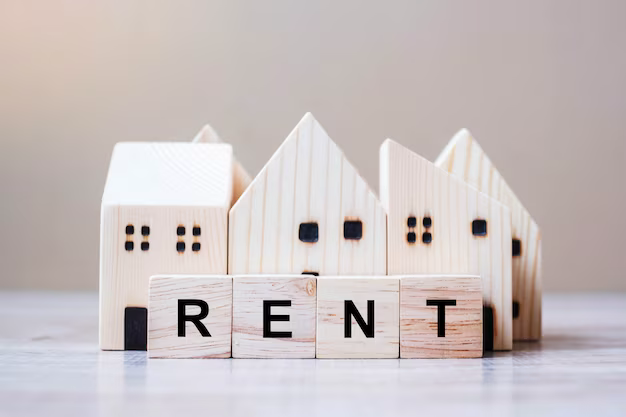 The word rent made from wooden cubes, wooden houses in the background