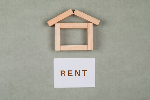 Wooden blocks in the shape of a house, next to it is a sticker with the inscription rent