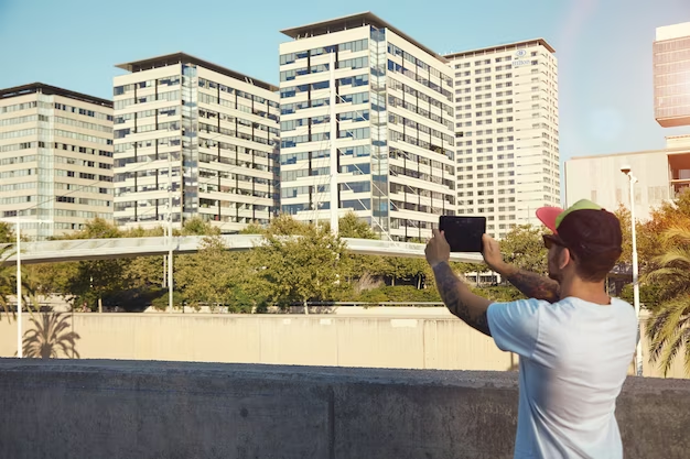 Man using a tablet to capture a distant shot of a condo building.