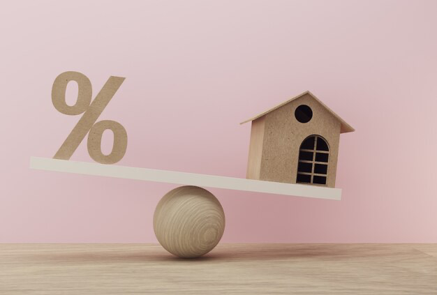 A wooden block with a figurine of a house and a percent holds balance on a ball
